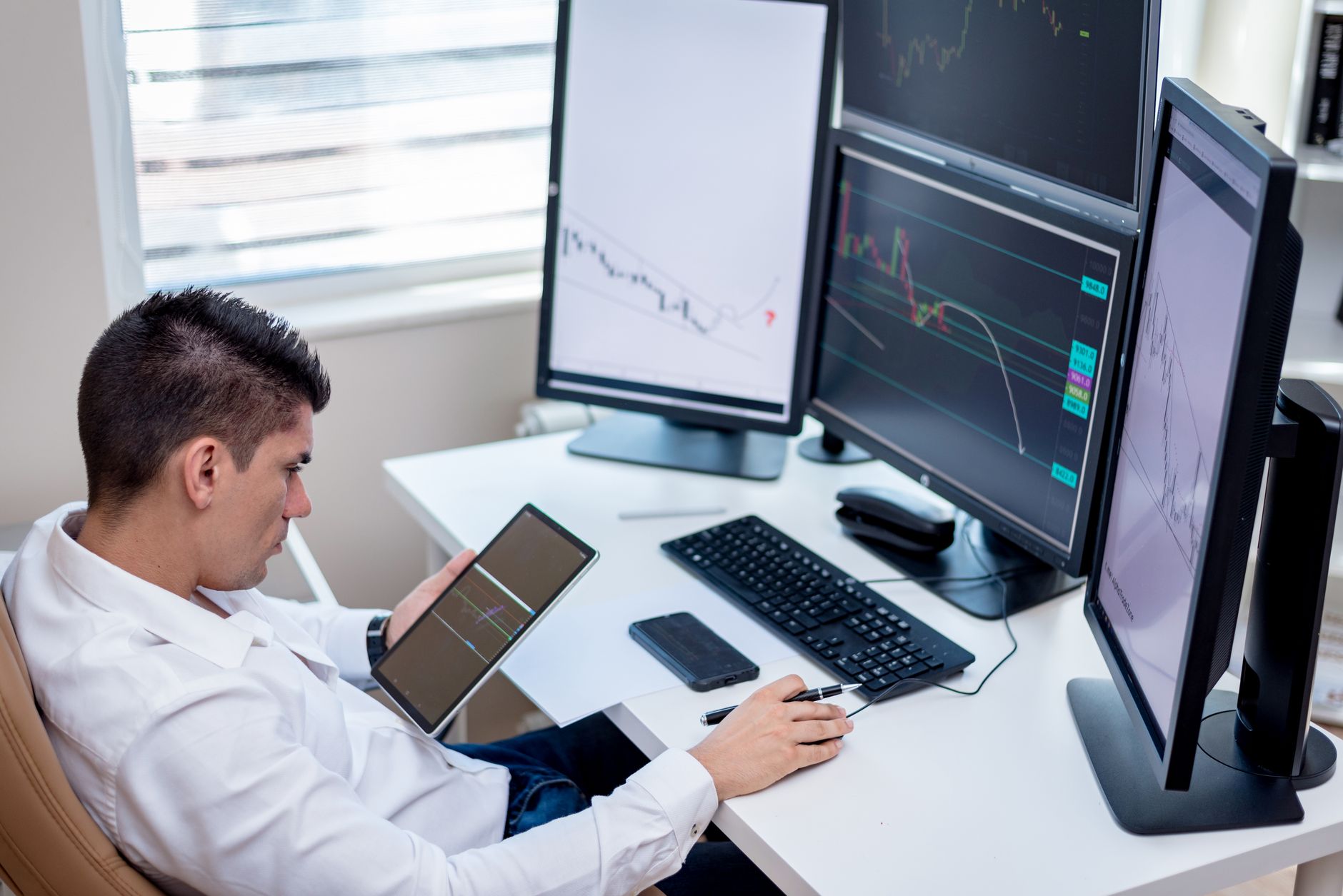 Trader at a desk reviewing fee and price charts across two monitors